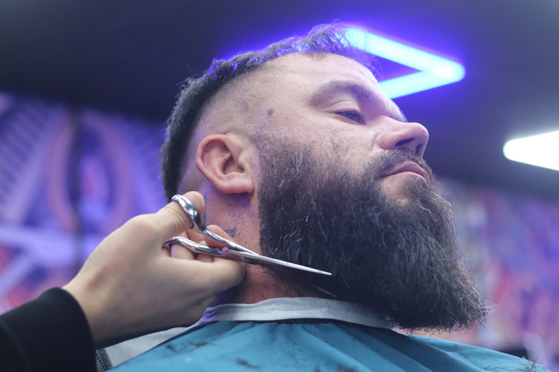Beard shaped with scissors under the neon ceiling